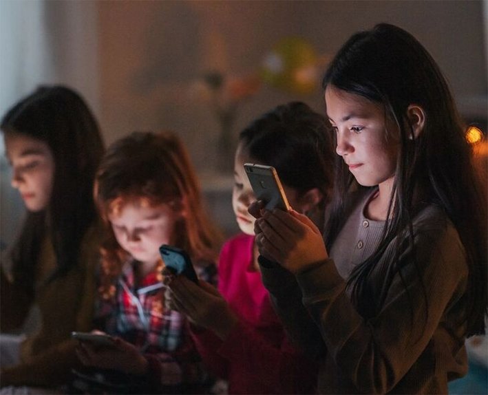 A teenager looking stressfully at a smartphone screen with blurred social media app icons floating in the background, in June 2026.